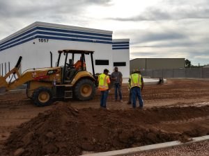 Workers and a backhoe beside the finished building, October 2021