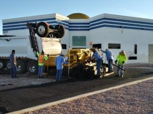 A paving machine laying asphalt beside the masjid